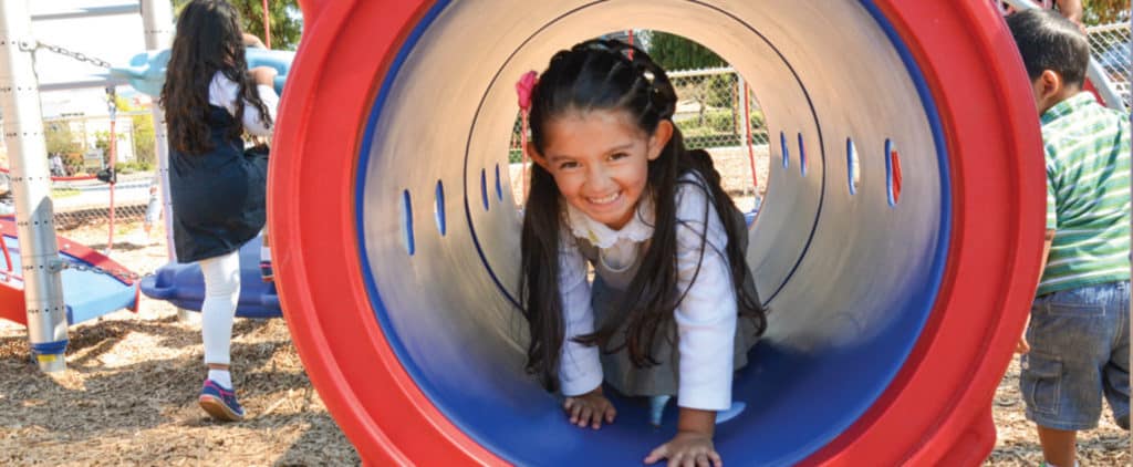 girl climbing through playground tunnel