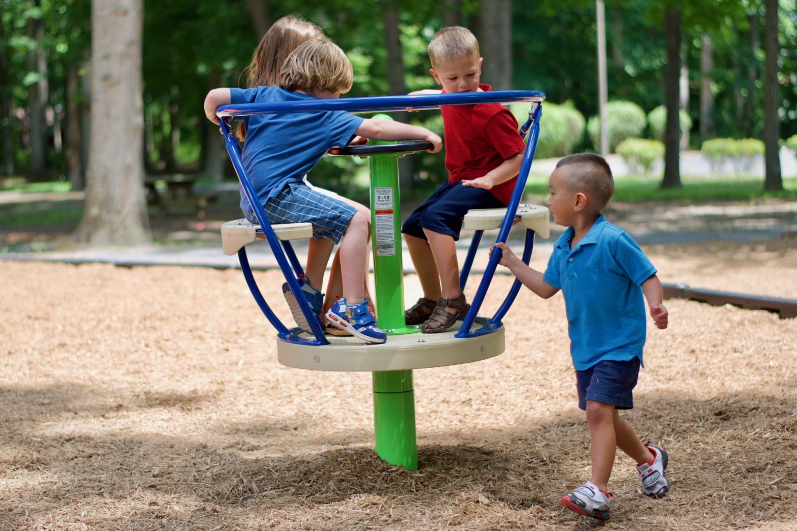 Four kids playing on a spinning playground equipment